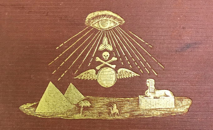 Embossed golden illustration on a maroon book cover featuring an eye emitting rays towards a skull and crossbones over wings, with pyramids, a palm tree, a sphinx, and a person in the foreground.